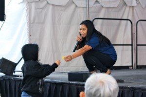 IMG_7898 Michelle Wong crouching on stage to hand something to a child during the Nite 'n Day festival