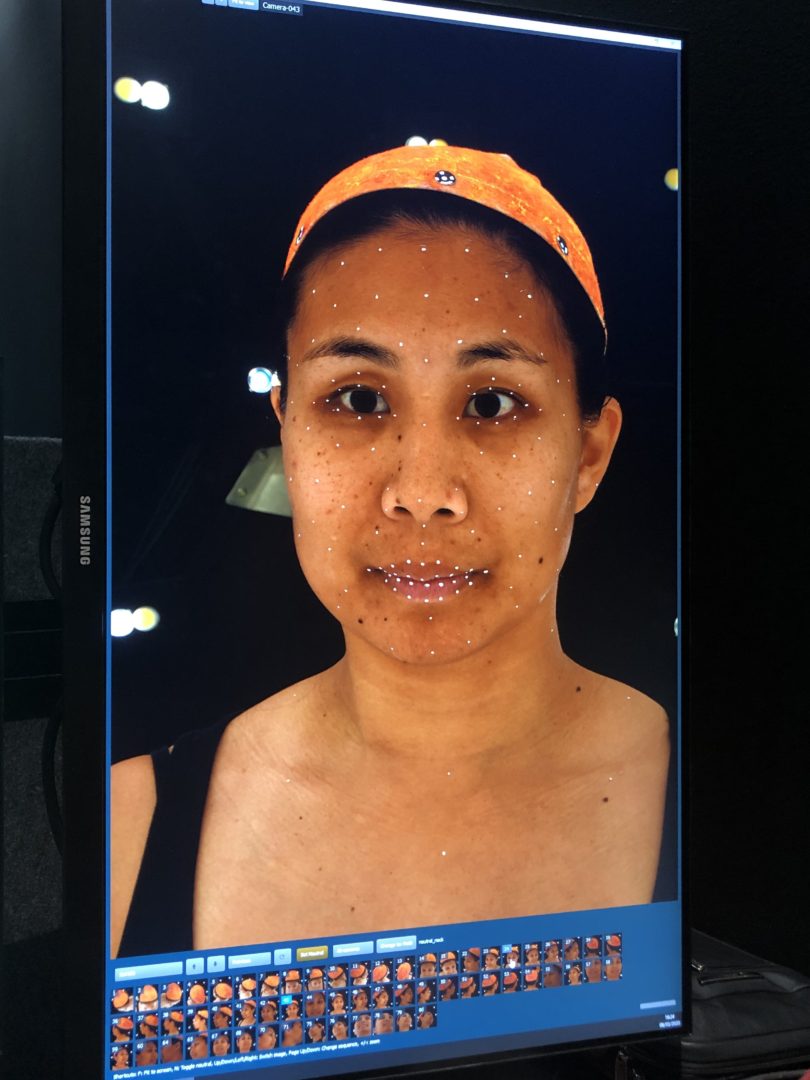 A monitor showing facial motion-capture tracking dots overlaid on Michelle Wong's face